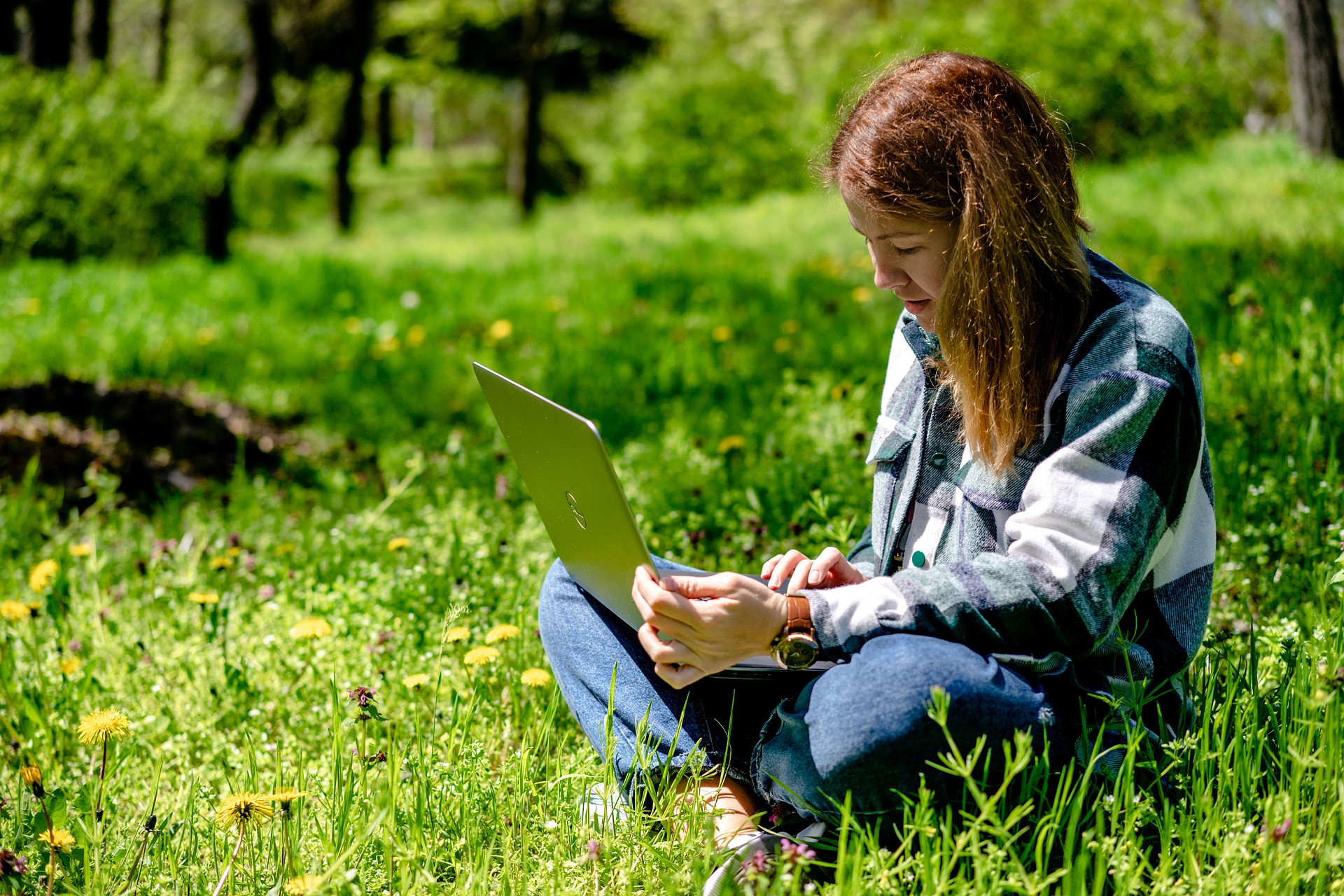 Frau sitzen mit Laptop in der Natur